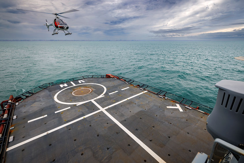 The modified Guimbal Cabri G2 lands on a civilian vessel equipped with a helicopter landing deck.