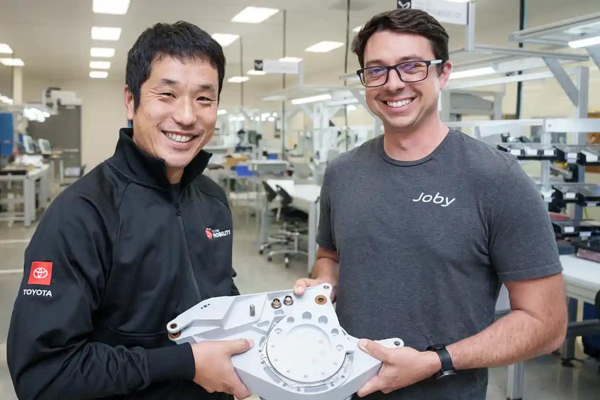 Kazuhiro Sato (left) and Jordin Gischler (right) present a completed tilt actuator, manufactured at Joby’s San Carlos production facility with key parts supplied by Toyota.