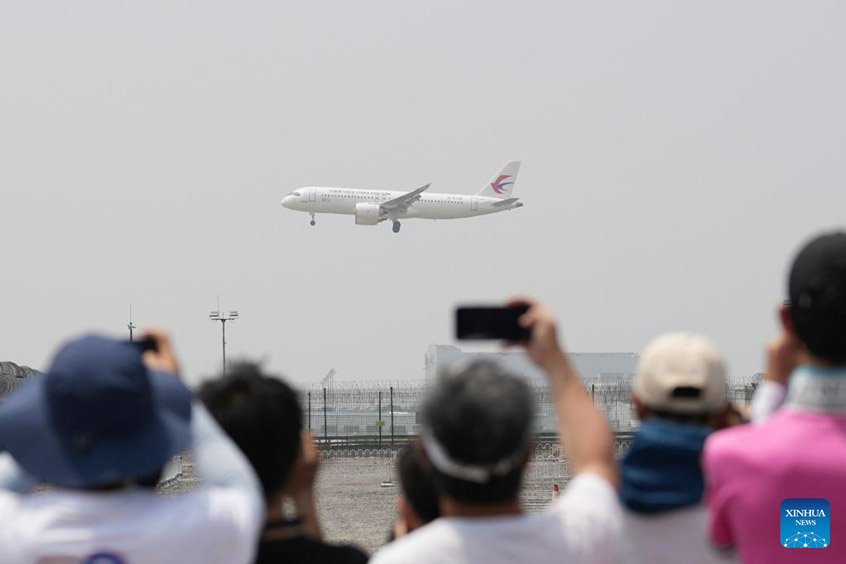 People take photos of a C919 large passenger aircraft, China's first self-developed trunk jetliner, before it lands at Beijing Capital International Airport, in Beijing, capital of China, May 28, 2023.